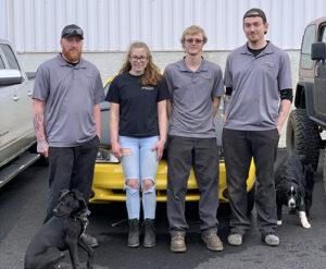 group pic with a black dog standing in front of a yellow car